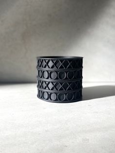 a stack of black bracelets sitting on top of a white table next to a wall