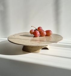 three cherries are sitting on top of a white platter in the sun light