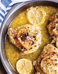 three pieces of chicken in a pan with lemons