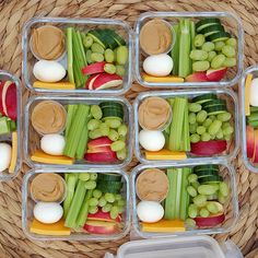 four plastic containers filled with food on top of a woven table cloth next to a basket