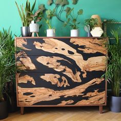 a wooden cabinet with plants and potted plants on it in front of a green wall