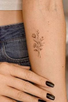 a woman's arm with tattoos on it and flowers tattooed on the left side