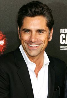 a smiling man in a black suit and white shirt