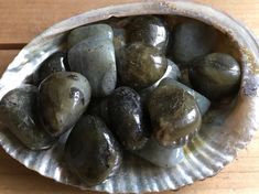 a bowl filled with green rocks on top of a wooden table