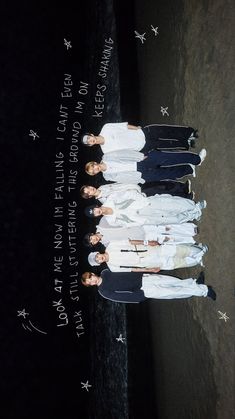 four people standing in front of the ocean with their arms around each other's shoulders