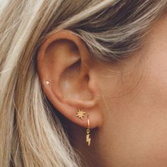 a close up of a woman's ear wearing gold earrings with stars on them