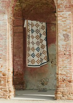 an old brick building with a quilt hanging from it's side wall and two doorways