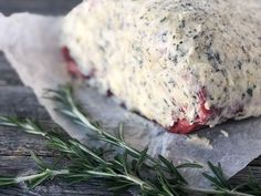 a piece of cheese sitting on top of wax paper next to a sprig of rosemary