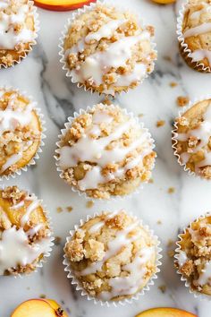 muffins with white icing and sliced peaches on a marble counter top