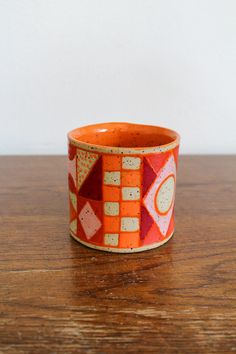 an orange and white cup sitting on top of a wooden table