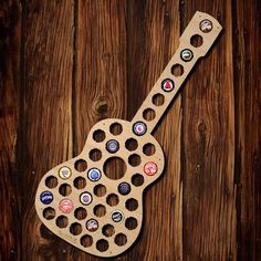 a wooden guitar shaped bottle cap holder on top of a wooden table next to a wall