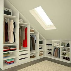 an attic closet with white shelving and lots of clothes