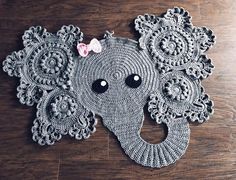 an elephant made out of crocheted doily on a wooden floor with a pink flower