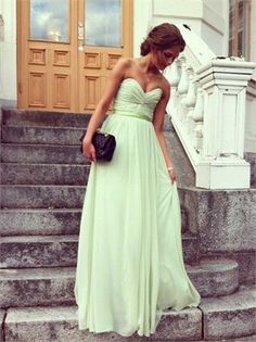 a woman in a green dress standing next to stairs