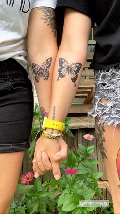 two people are holding hands with tattoos on their arms and both have yellow bracelets