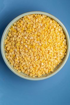 a bowl filled with corn on top of a blue table