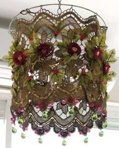 a chandelier hanging from the ceiling with flowers and leaves on it's sides