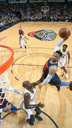 the basketball player is going to dunk the ball in front of the other players