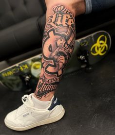 a man's leg with a tattoo on it and his skateboard in the background