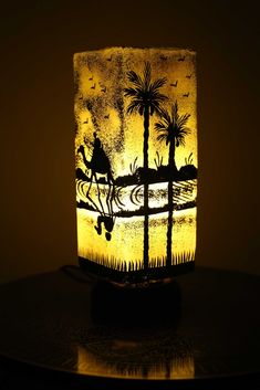 a lamp that is sitting on top of a table with a horse and palm trees