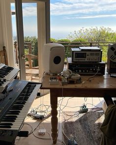 an electronic keyboard sitting on top of a wooden table in front of a large window