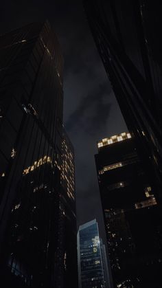 two tall buildings are lit up in the dark sky at night with lights on them