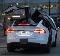 the back end of a white car with its doors open