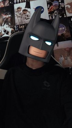 the lego batman mask has glowing eyes and is sitting in front of a bunch of pictures