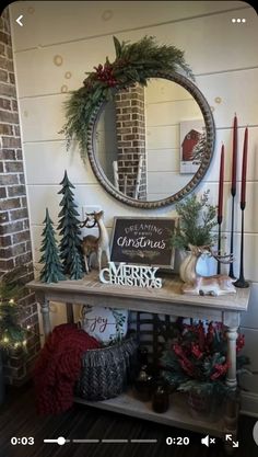 a table with christmas decorations on it in front of a brick wall and a round mirror