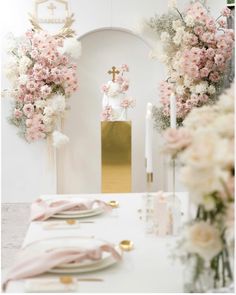 a white table topped with pink flowers and gold place settings in front of a church altar