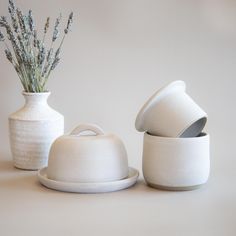 three white vases with flowers in them on a table