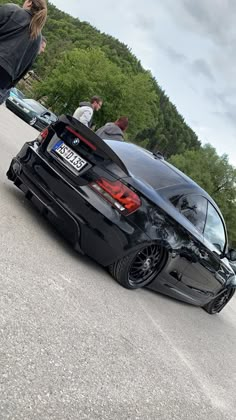 a black car parked on the side of a road next to a person standing in front of it