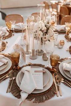 the table is set with white and gold plates, silverware, and napkins