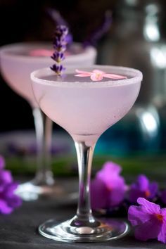 two martinis with lavender garnish sit on a table next to purple flowers