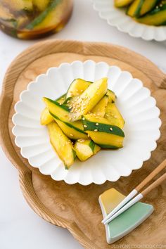 a white plate topped with sliced cucumbers on top of a wooden platter