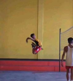 a man jumping in the air while holding onto a volleyball racket and another person watching