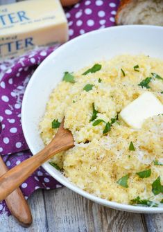 a white bowl filled with mashed potatoes and parmesan cheese next to bread