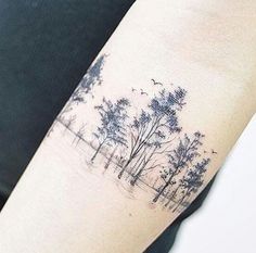 a person with a small tattoo on their arm that has trees and birds in it