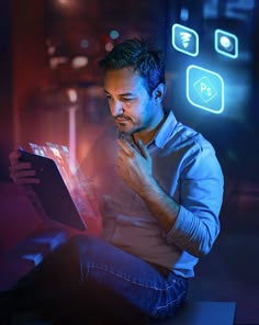 a man sitting on the floor looking at something in front of him with neon lights behind him