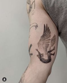 a man with a tattoo on his arm that has birds flying in the sky above him