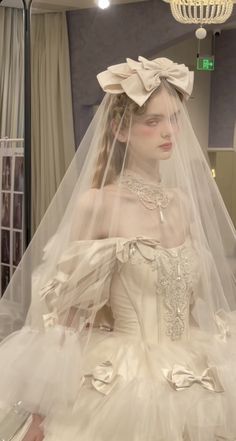 a woman in a white wedding dress with a veil on her head and a chandelier hanging from the ceiling