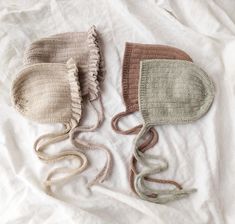 three knitted hats laying on top of a white sheet