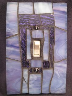 a decorative light switch cover with purple and white tiles