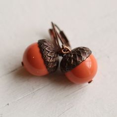 These beautiful acorn earrings are made from a pearl with an antique copper bead cap.  The tones of the tarnished red copper with the warm coral orange of the pearl look great together.  I have added some co-ordinating copper ear wires.   The length of the earring is about 30mm (just over an inch) long.  This piece of handmade jewellery comes packaged in a nice recycled gift box with a handmade tag, all ready to give or keep. We have more acorn earrings and necklaces here: https://www.etsy.com/uk/shop/SilkPurseSowsEar?ref=hdr_shop_menu&search_query=acorn 🖤 FASTER SHIPPING 🖤 Need this fast? We offer a Faster Shipping option here: https://www.etsy.com/uk/listing/100107311/faster-shipping-priority-post-upgrade Please read the description before purchasing this listing, as we are unable to p The Tarnished, Acorn Earrings, Silk Purse, Red Copper, Tangerine Orange, Handmade Tags, Coral Orange, Swarovski Pearls, Pearl Color