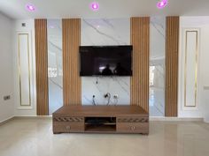 a flat screen tv sitting on top of a wooden stand in front of a marble wall