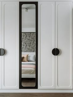 a bedroom with white cabinets and black handles