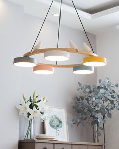 a light fixture hanging from the ceiling above a table with flowers and vases on it