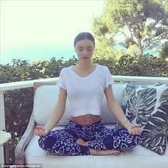 a woman is sitting in the middle of a yoga pose on a couch with her legs crossed