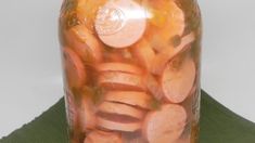 a jar filled with sliced carrots sitting on top of a green shirt next to a mannequin