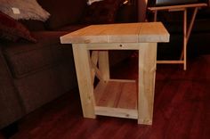 a small wooden table sitting on top of a hard wood floor next to a couch